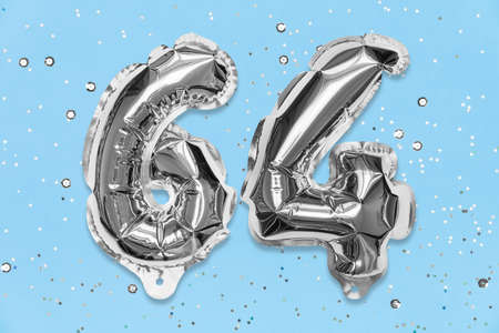 Silver foil balloon number, digit sixty four on a blue background with sequins. Birthday greeting card with inscription 64. Top view. Numerical digit. Celebration event, template.の写真素材