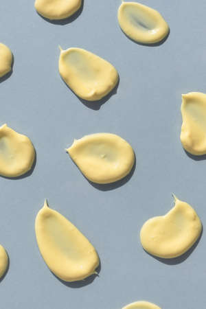 Yellow cream texture on a gray background. Smears of skincare cosmetics product. wellness and beauty concept. top view.の写真素材
