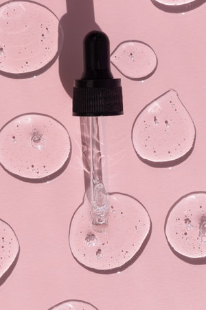 Drops of serum or hyaluronic acid gel with a pipette on a pink background. Smears of cosmetic skin care products. wellness and beauty conceptの写真素材