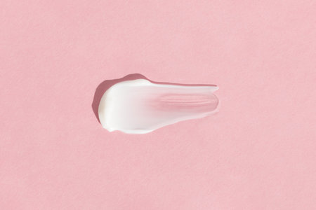 White cream texture on a pink background. A smear of a cosmetic skin care product. wellness and beauty concept. top viewの写真素材