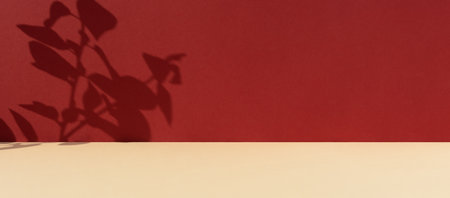 Premium podium with a shadow of plant leaves on a red wall and a beige table. Minimal abstract background for the presentation of a cosmetic product. Show case, display case.の写真素材