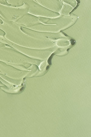 Transparent serum gel with hyaluronic acid for the face on a green background. The texture of a cosmetic product with oxygen bubbles. wellness and beauty concept.の写真素材