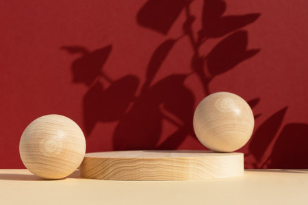 Wooden scenes of different geometric shapes on a beige table with the shadow of plant leaves on a red wall. Premium podium for advertising and presentation of your product. Showcase, display case.の写真素材