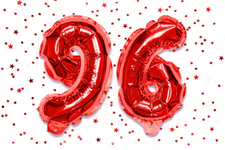 The number of the balloon made of red foil, the number ninety-six on a pink background with sequins. Birthday greeting card with inscription 96. Numerical digit. celebration event.の写真素材