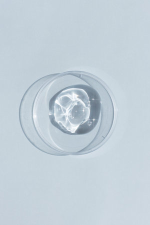 Hyaluronic acid serum or gel for the face in Petri dish on a gray background. Concept of cosmetics laboratory researches, wellness and beauty. cosmetic texture. top viewの写真素材