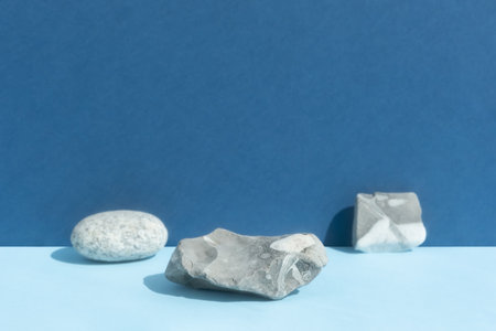 Empty podium made of gray stone on a blue background. Scene for the promotion of products, beauty, natural eco-cosmetics. Show case, display case.の写真素材