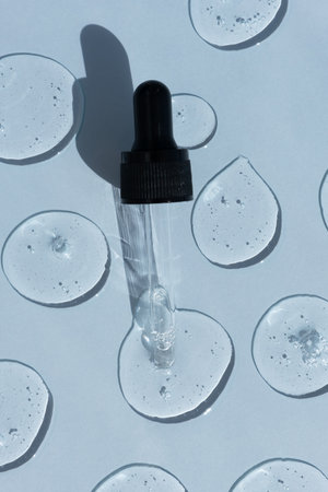 Drops of serum or hyaluronic acid gel with a pipette on a blue background. Smears of cosmetic skin care products. wellness and beauty concept.の写真素材