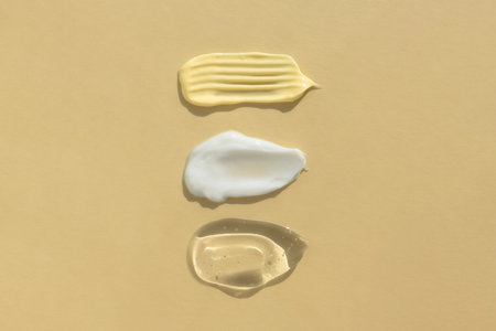 Smears of yellow, white cream and transparent gel or serum on a beige background. The texture of a cosmetic skin care product. top view.の写真素材