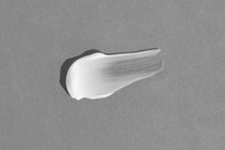 White cream texture on a gray background. A smear of a cosmetic skin care product. Wellness and beauty concept. Top view.の写真素材