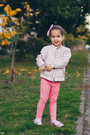 Young girl in a pink jacket and pink leggings in the parkの写真素材