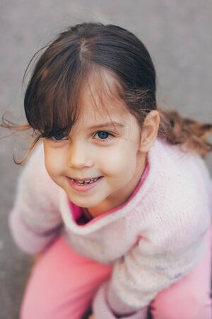 Young girl in a pink jacket and pink leggings in the parkの写真素材