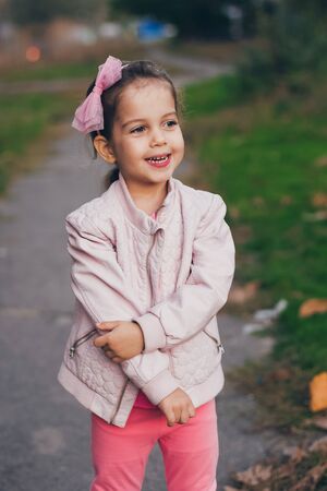 Young girl in a pink jacket and pink leggings in the parkの写真素材