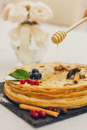 Plate of pancakes dripping with caramel with cranberries and blueberries, cinnamon sticks. Shrovetide Maslenitsa Butter Week festival meal. Shrove Tuesday. Pancake day.の写真素材