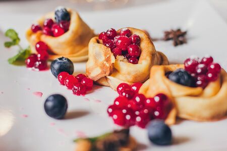 Plate of pancakes dripping with caramel with cranberries and blueberries, cinnamon sticks. Shrovetide Maslenitsa Butter Week festival meal. Shrove Tuesday. Pancake day.の写真素材