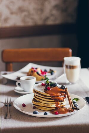 Plate of pancakes dripping with caramel with cranberries and blueberries. Shrovetide Maslenitsa Butter Week festival meal. Shrove Tuesday. Pancake day.の写真素材