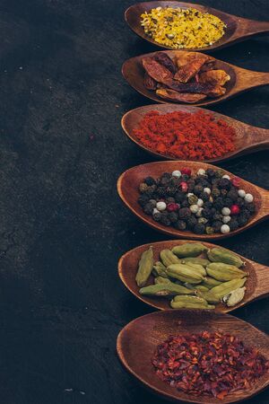 Colorful various spices in wooden spoons on old dark background. Top view with free spaceの写真素材