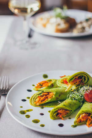 Healthy fresh green spinach pancakes stuffed with vegetables served on the table in the restaurant