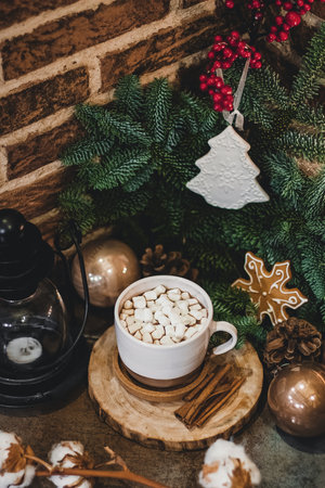 Christmas hot chocolate with mini marshmellows in an old ceramic mug with candles on a wooden background.の写真素材