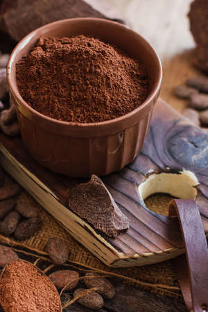 Unsweetened baking block chocolate, cocoa powder, cocoa butter and cocoa beans on old wooden background.の写真素材