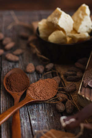 Unsweetened baking block chocolate, cocoa powder, cocoa butter and cocoa beans on old wooden background.の写真素材