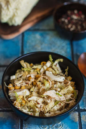 Salad with cabbage, eggs, corns and meat on the plate on rustic tiled table.の写真素材