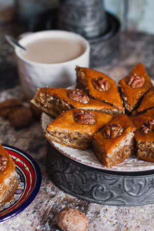 Assorted baklava. A Turkish ramadan arabic sweet dessert on a decorative plate, with coffee cup in the background. Middle eastern food baklava with nuts and honey syrupの写真素材