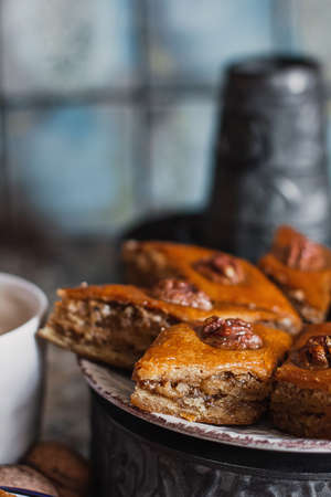 Assorted baklava. A Turkish ramadan arabic sweet dessert on a decorative plate, with coffee cup in the background. Middle eastern food baklava with nuts and honey syrupの写真素材