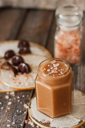 Homemade salted caramel sauce in jar on vintage background.の写真素材