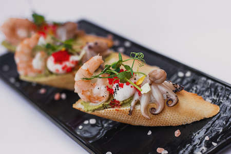 Seafood bruschetta toasted bread topped with fresh salad, egg, greens, shrimp, octopusの写真素材