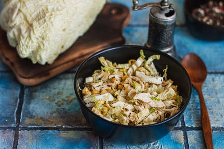 Salad with cabbage, eggs, corns and meat on the plate on rustic tiled tableの写真素材