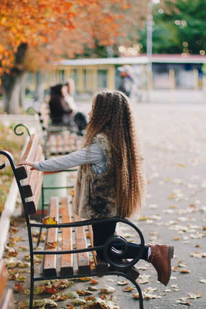Stylish baby girl 4-5 year old wearing boots, fur coat, moving and playing. Autumn fall seasonの写真素材