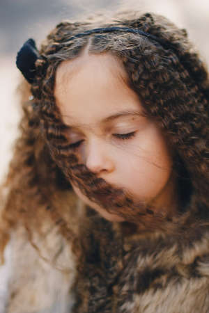 Stylish baby girl 4-5 year old wearing boots, fur coat, moving and playing. Autumn fall season