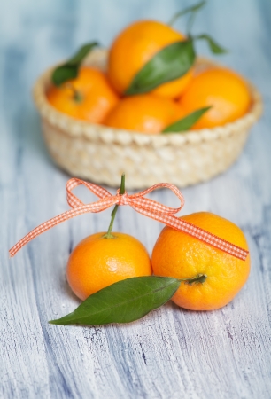 Two mandarins on the old blue-white table near the basket with mandarinsの写真素材