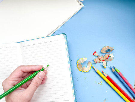 Notepad and diary on a colored background. Colored pencils, compasses, hand draws, children's hand. sharpened pencils.の写真素材