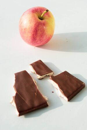 tiles of milk chocolate and apple on a white background, healthy food