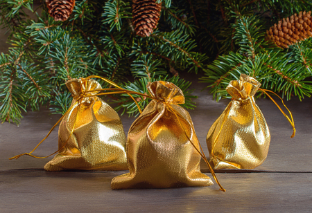 Golden gift bags on the background of spruce conesの写真素材