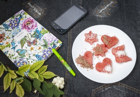 notebook, pen and smartphone near a plate of watermelonの写真素材