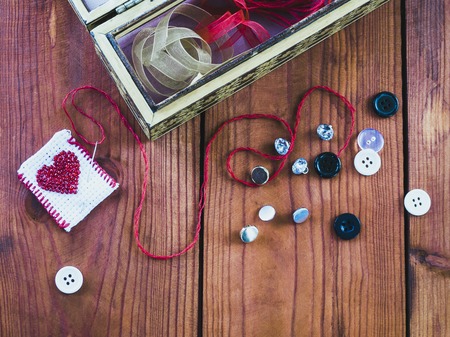 needle , thread and buttons on a wooden table