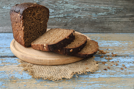 Sliced loaf of homemade bread on board on wooden background.の写真素材