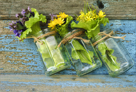 bouquets yellow flowers in glass bottle on old wooden surface.の写真素材