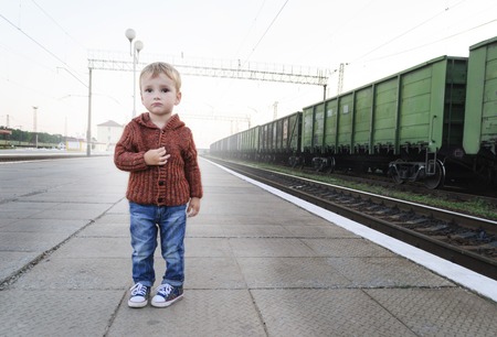 the little boy is standing at the railway stationの写真素材