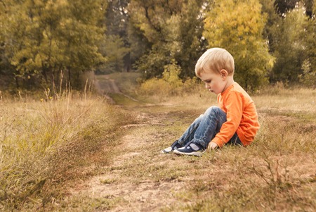 little boy is sad, sitting on the ground. Copyspaceの写真素材