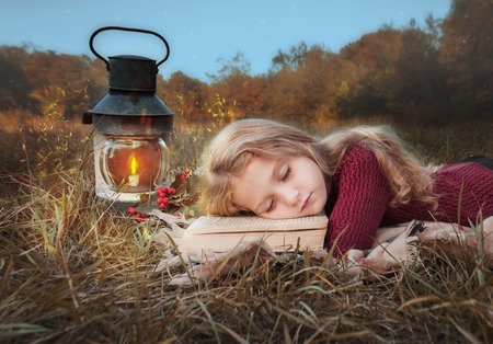 A little girl is sleeping with a book in the forest .の写真素材
