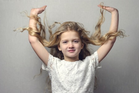 beautiful little girl with long blond hair on grey backgroundの写真素材