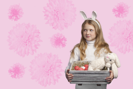 Little blonde girl holding box with painted eggs.の写真素材