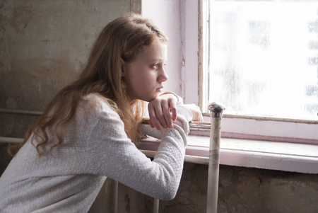 Depressed young girl sitting in the abandoned building.の写真素材