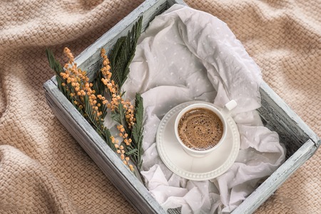 Cup of coffee and a wooden box on a knitted plaidの写真素材