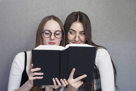 Two female students with books on a gray backgroundの写真素材