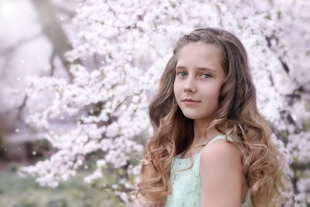 beautiful little girl on the background of a flowering treeの写真素材