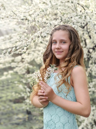 beautiful little girl on the background of a flowering treeの写真素材